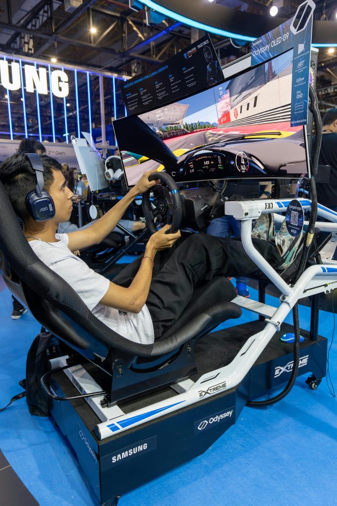 A man intensely plays a racing simulator at a tech event using advanced equipment.